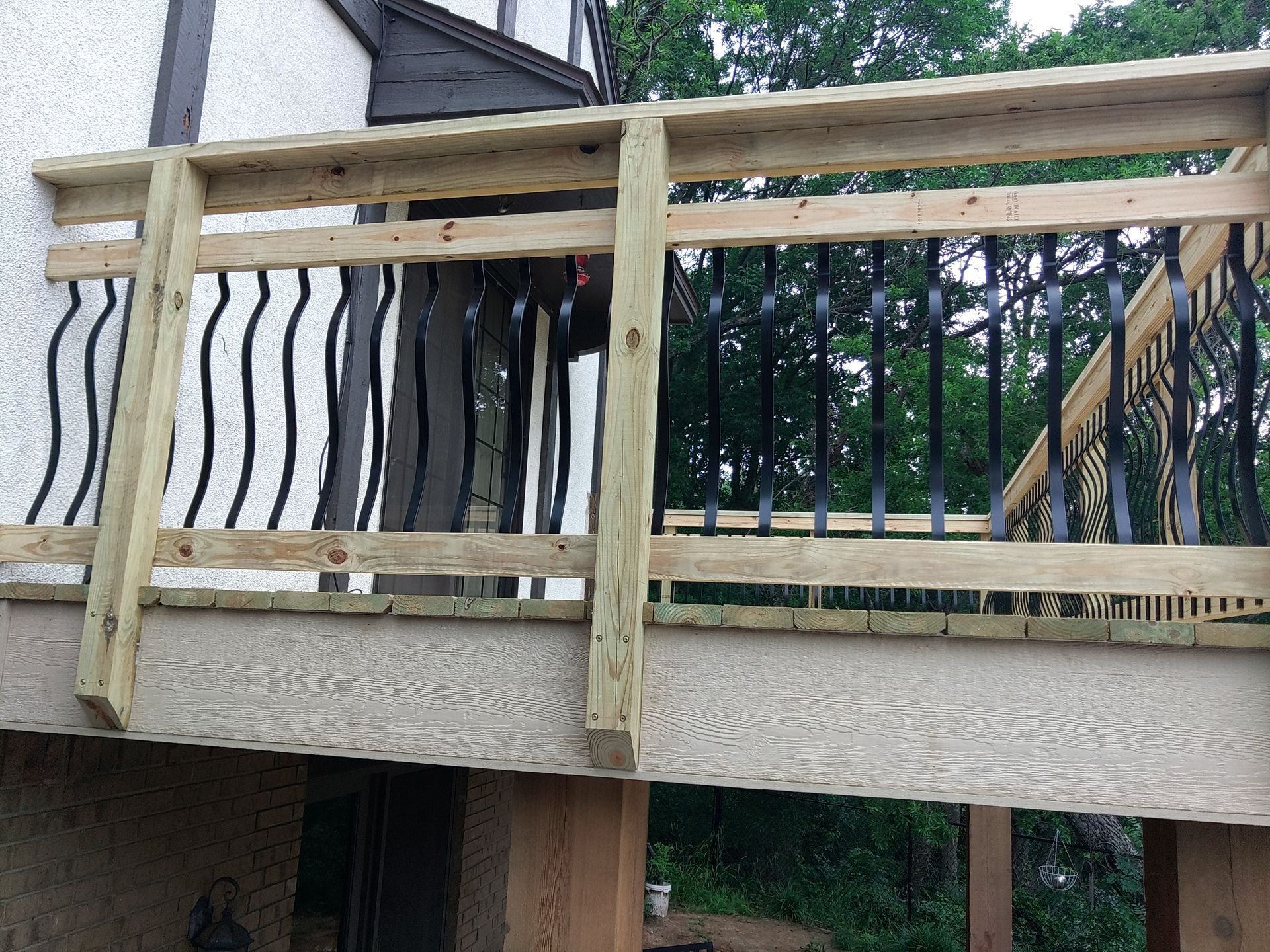 A wooden deck with a metal railing is being built on the side of a house.