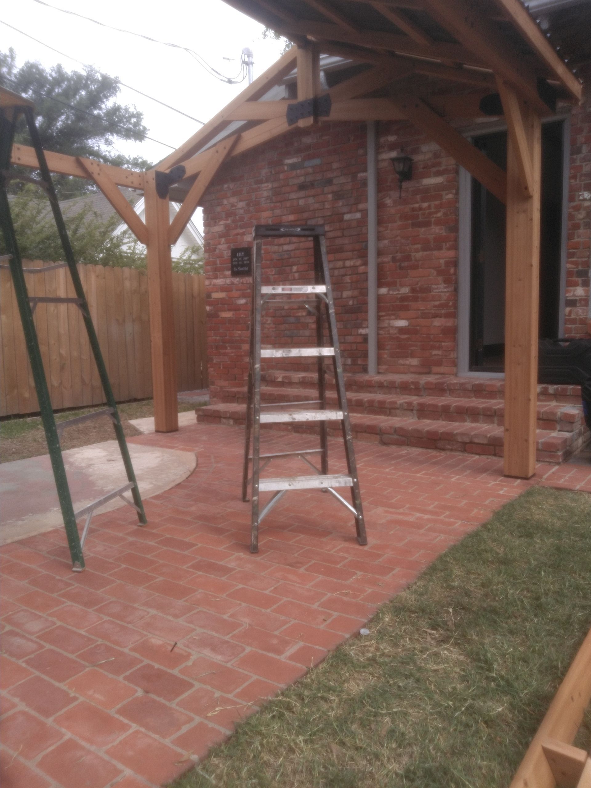 A ladder is sitting on a brick patio in front of a brick building