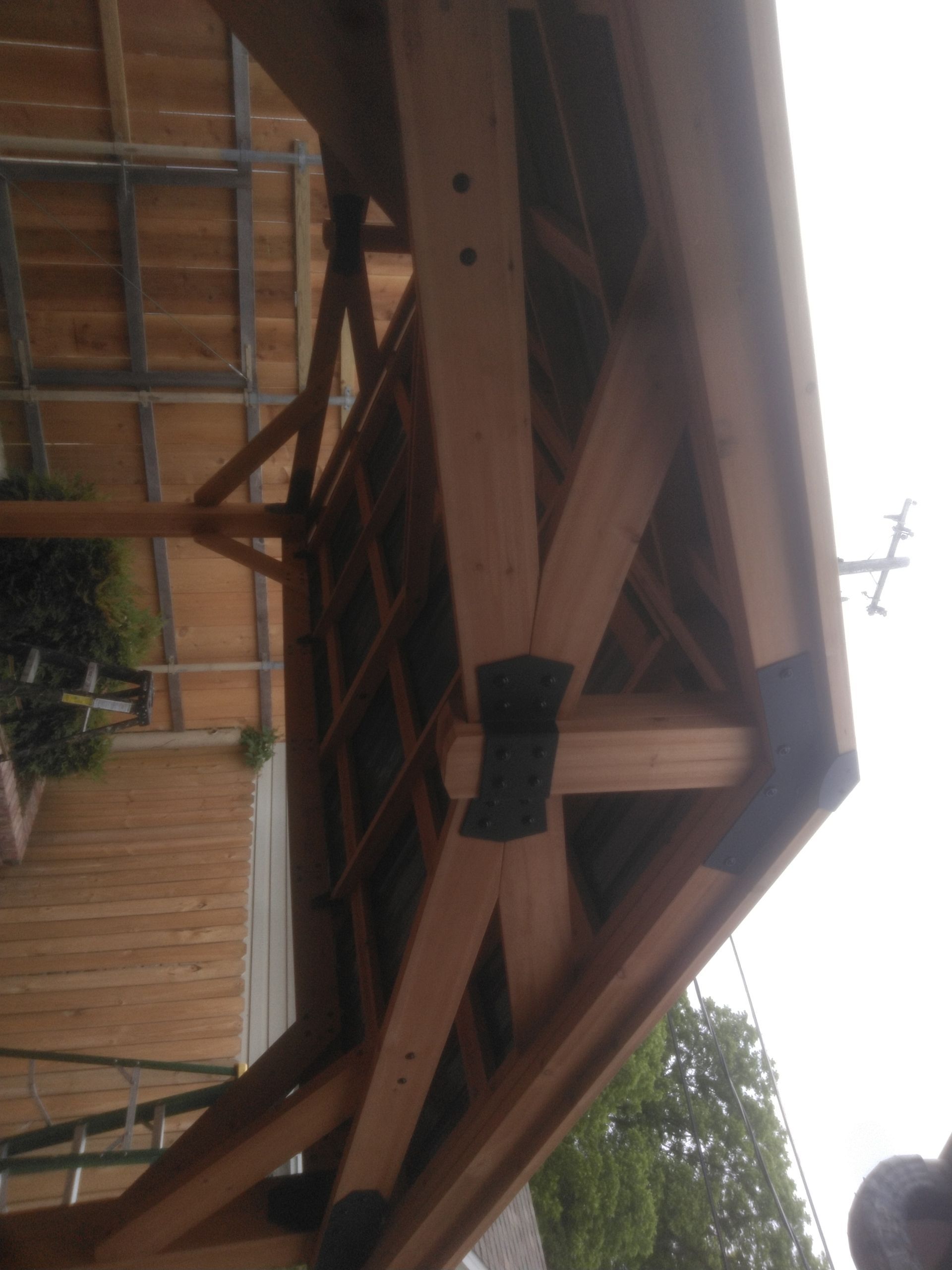 A wooden structure with a roof and a fence in the background