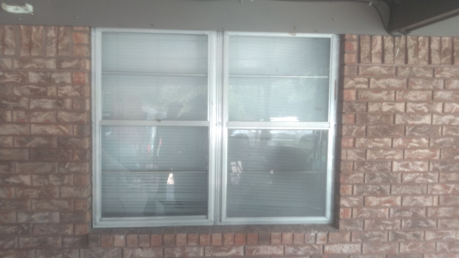 A brick wall with a window and blinds on it.