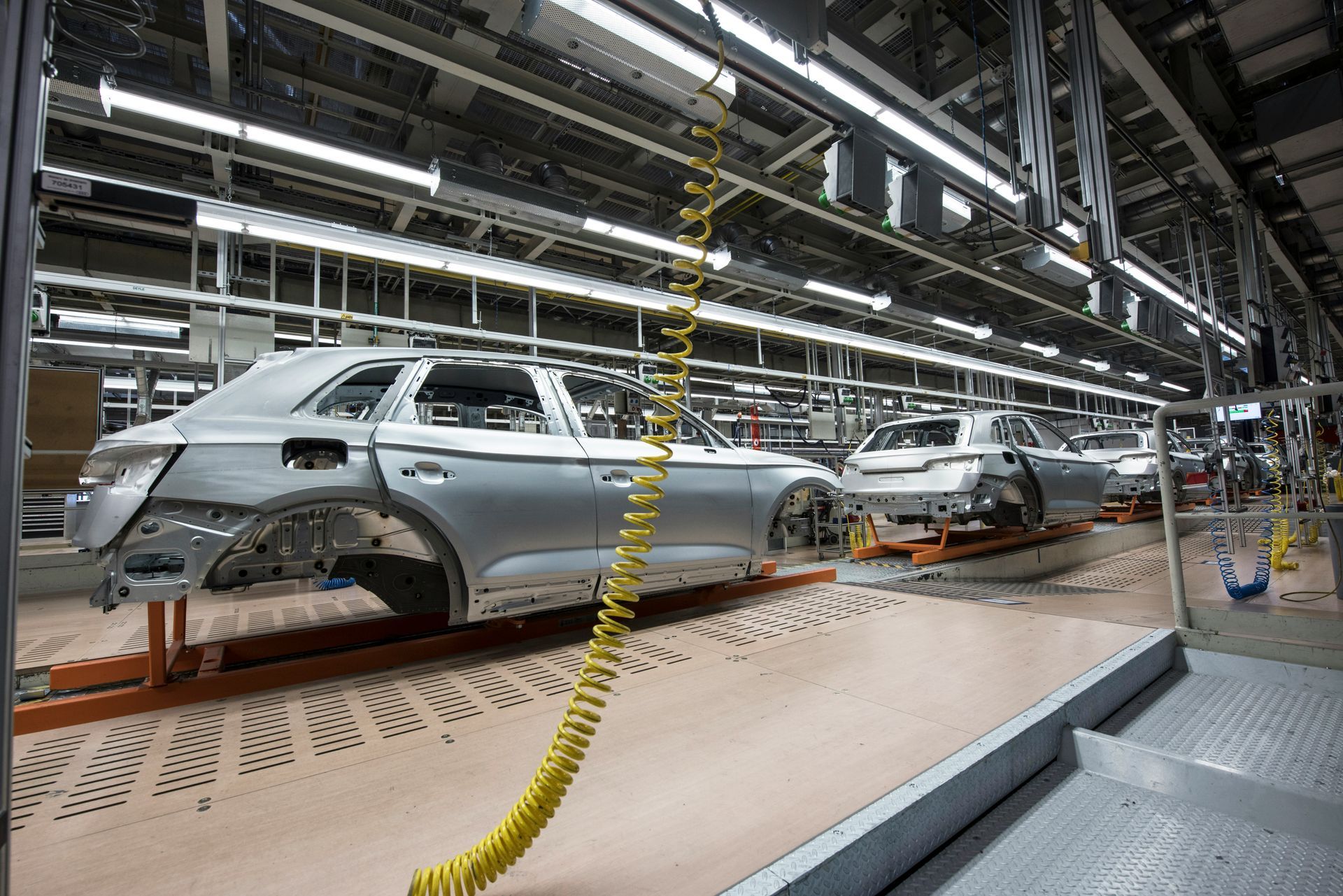 A row of cars are on a conveyor belt in a factory