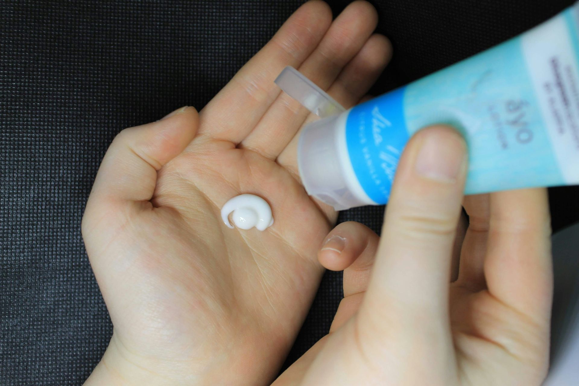A person is holding a tube of lotion in their hand