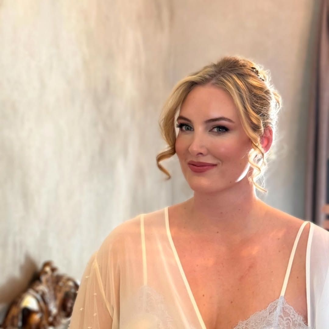 Donna bionda in vestaglia chiara, che guarda la telecamera. Interno, luci soffuse.