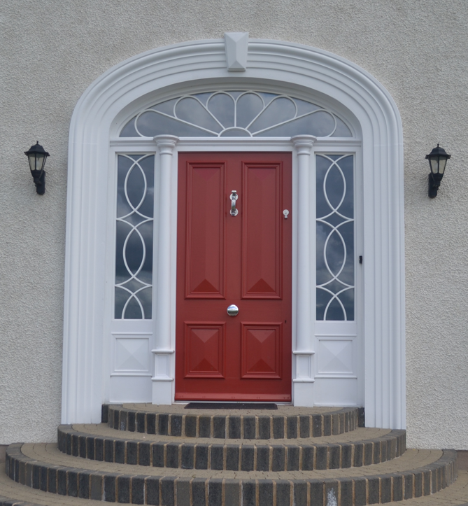 A red door on a white building with steps leading up to it