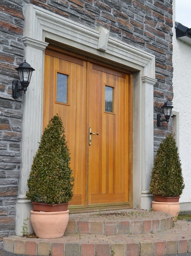 A wooden door with two potted plants in front of it