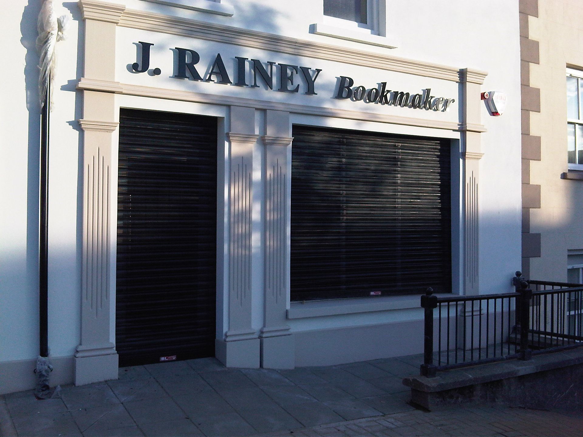 A white building with a sign that says j. rainey bookmaker