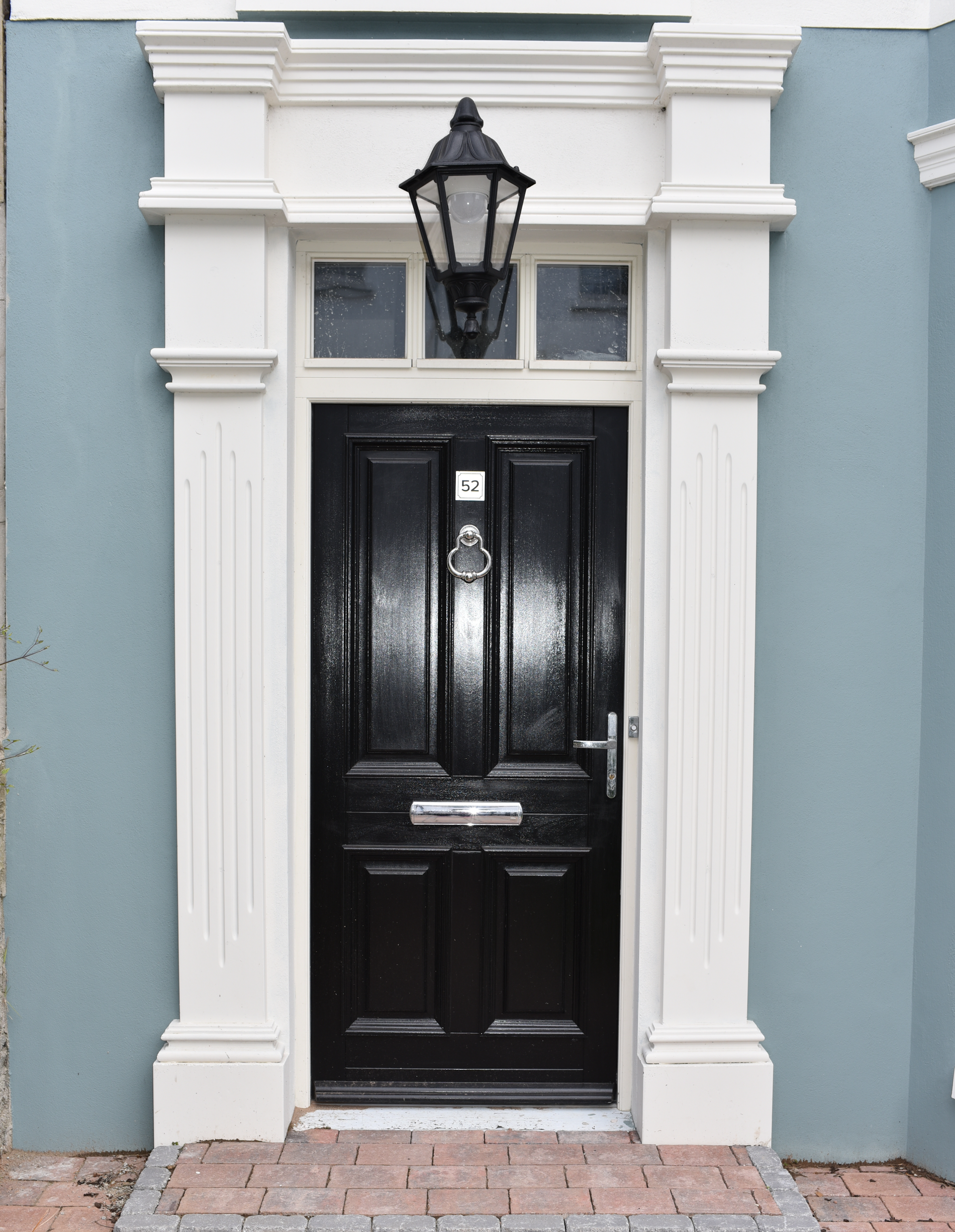 A black door with a lamp on top of it