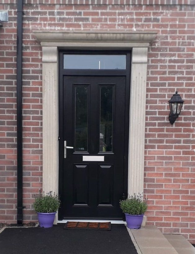 A black door with purple potted plants in front of it