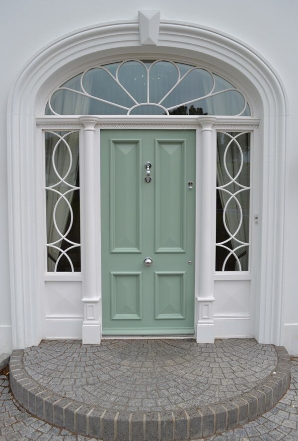 The front door of a white house with a green door