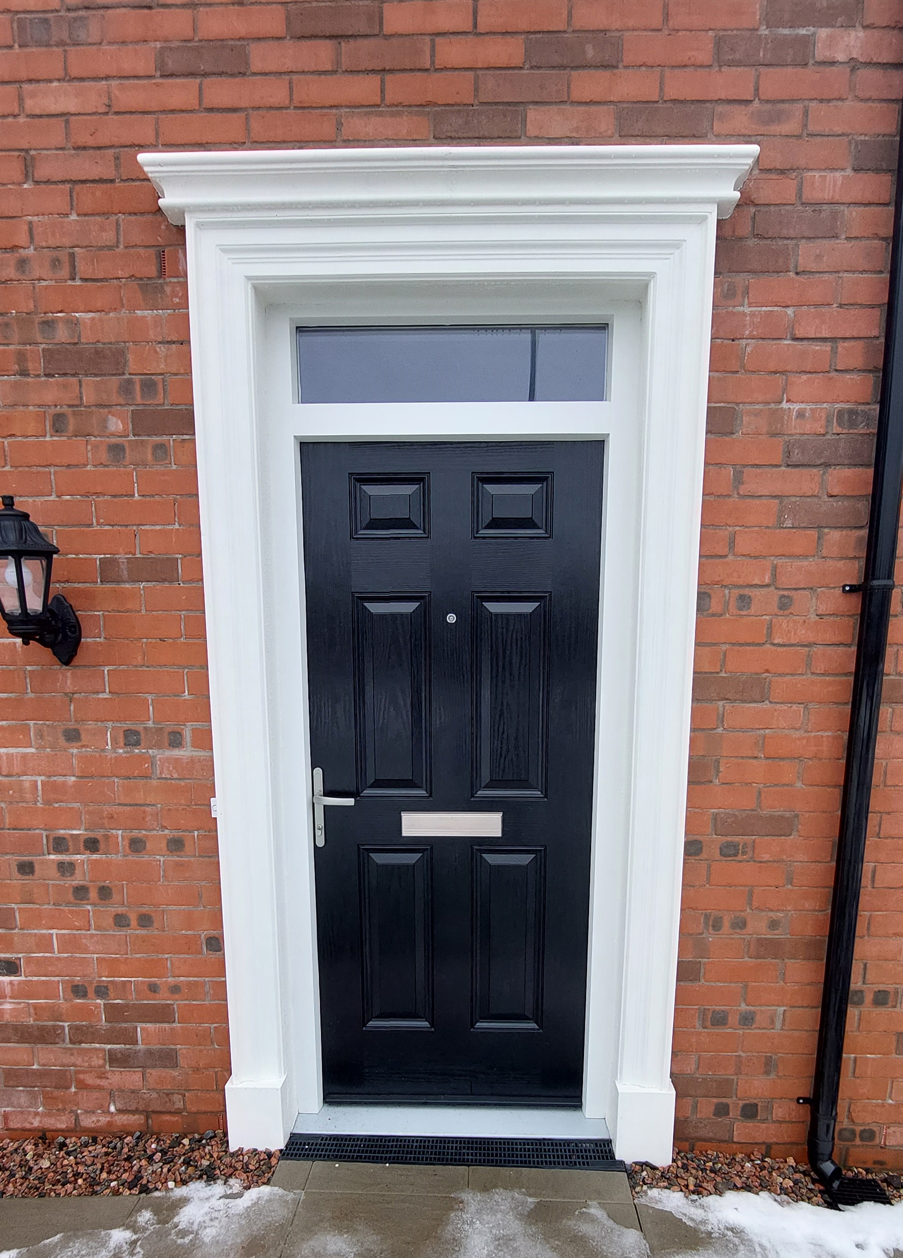 A black door with a white trim is on a brick building.