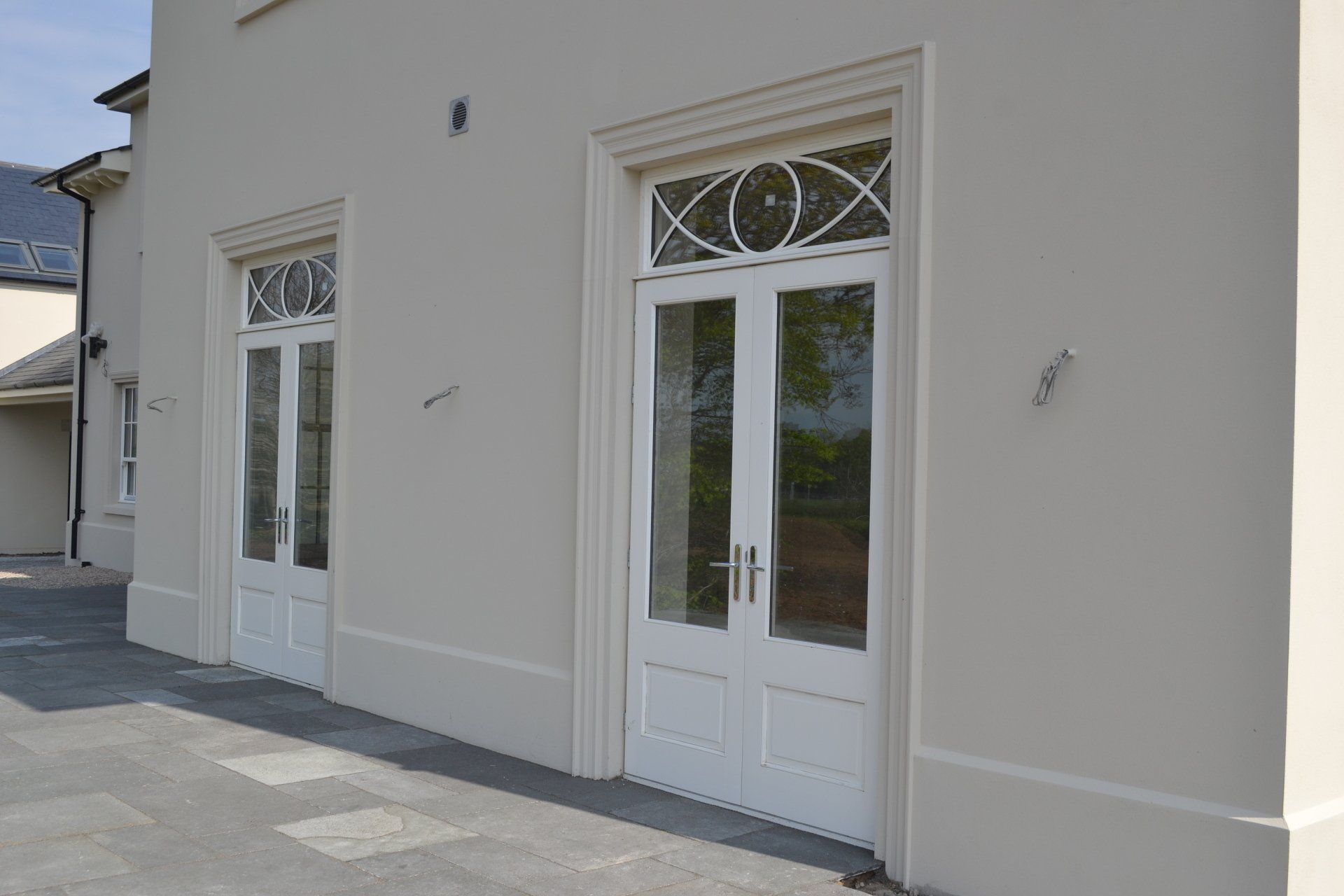 There are two white doors on the side of a building.