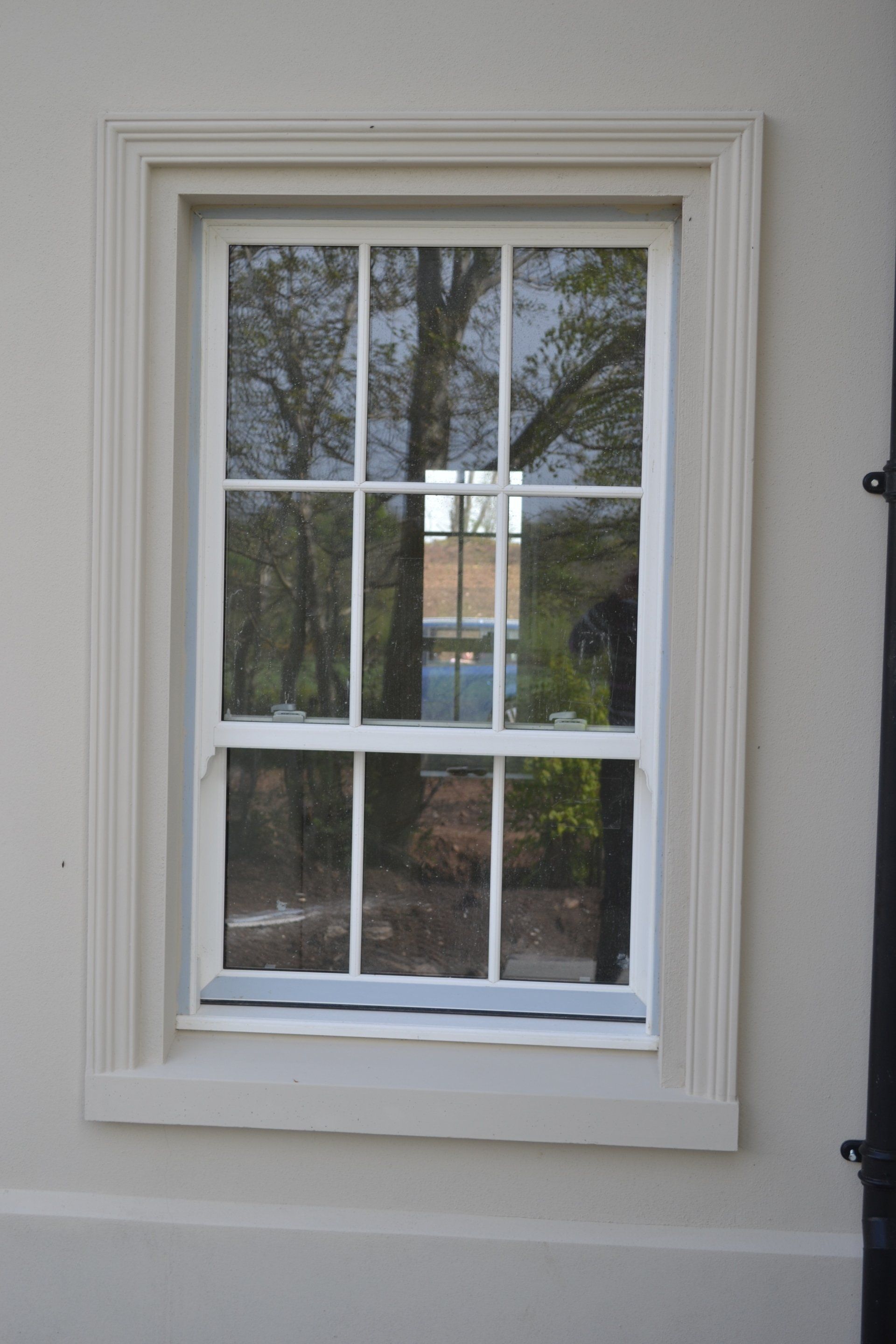 A white window with a reflection of trees in it