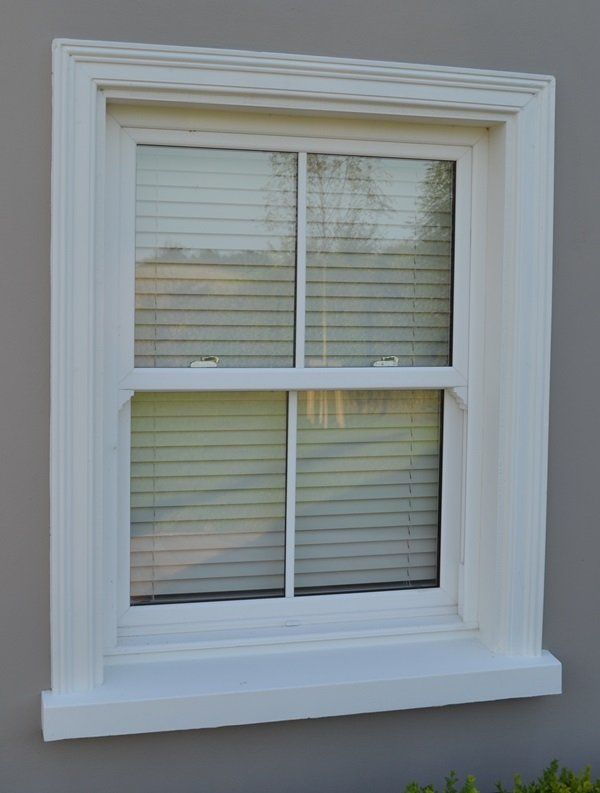 A white window with blinds is on a gray wall