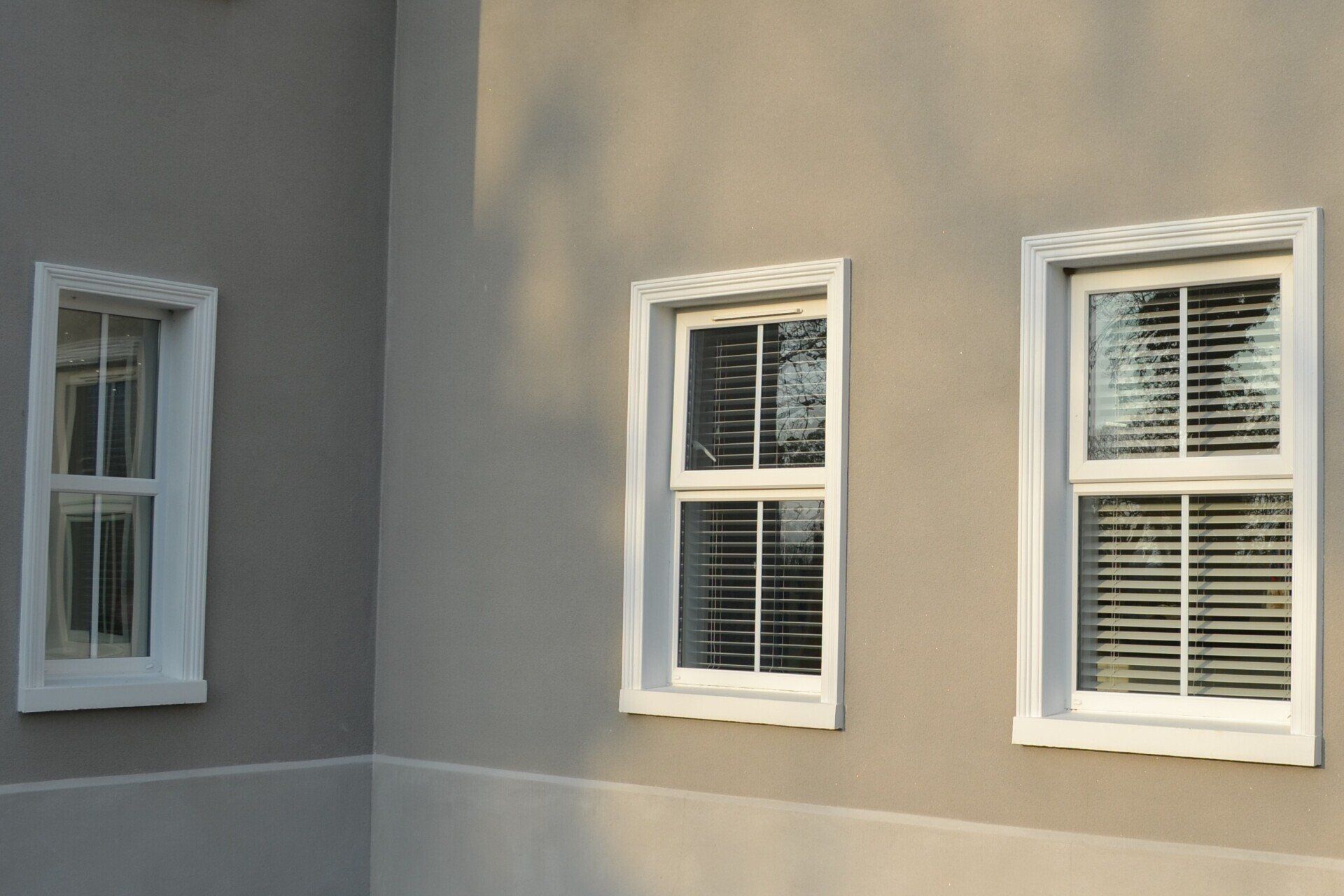 Three windows on the side of a building with blinds