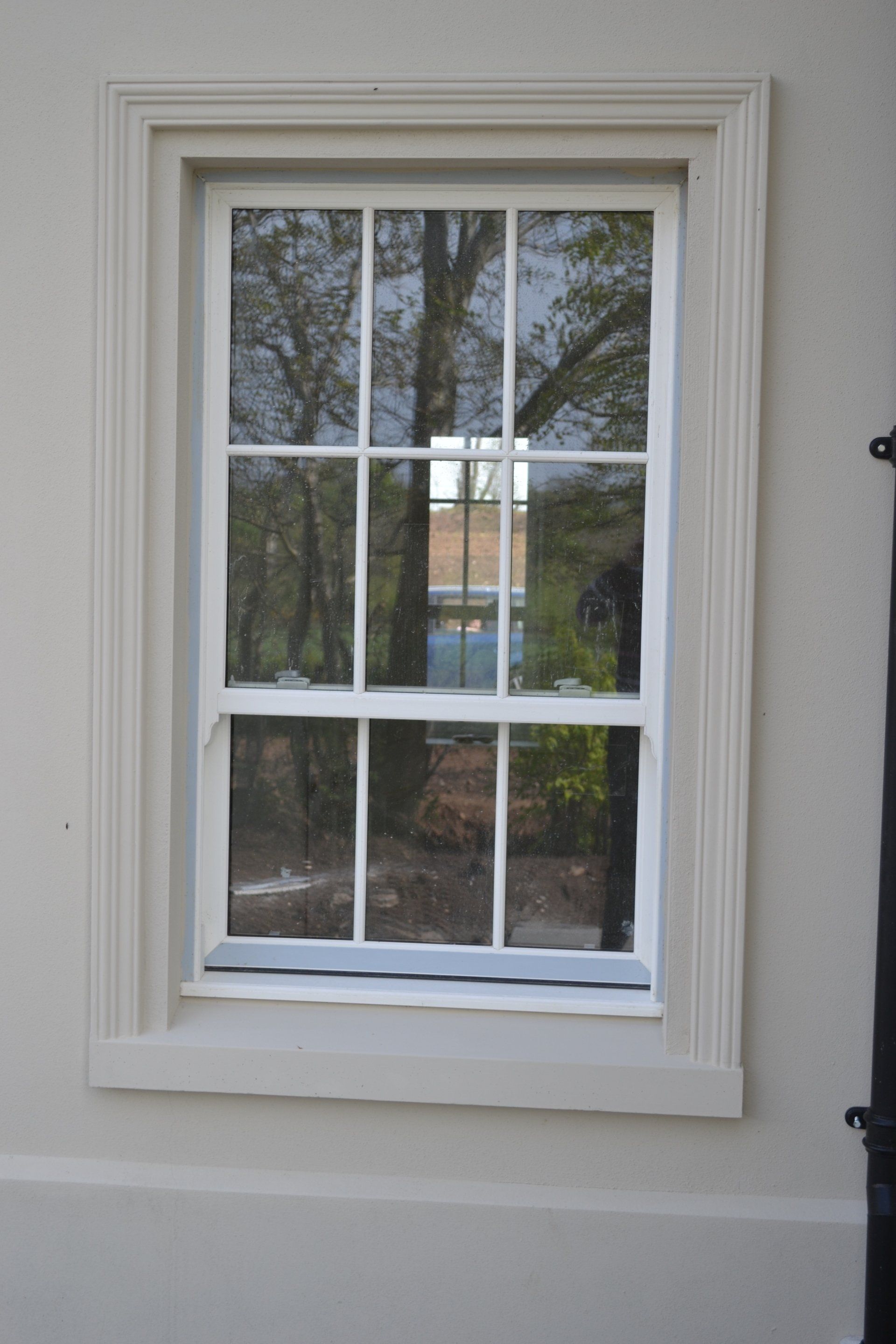 A white window with a reflection of trees in it