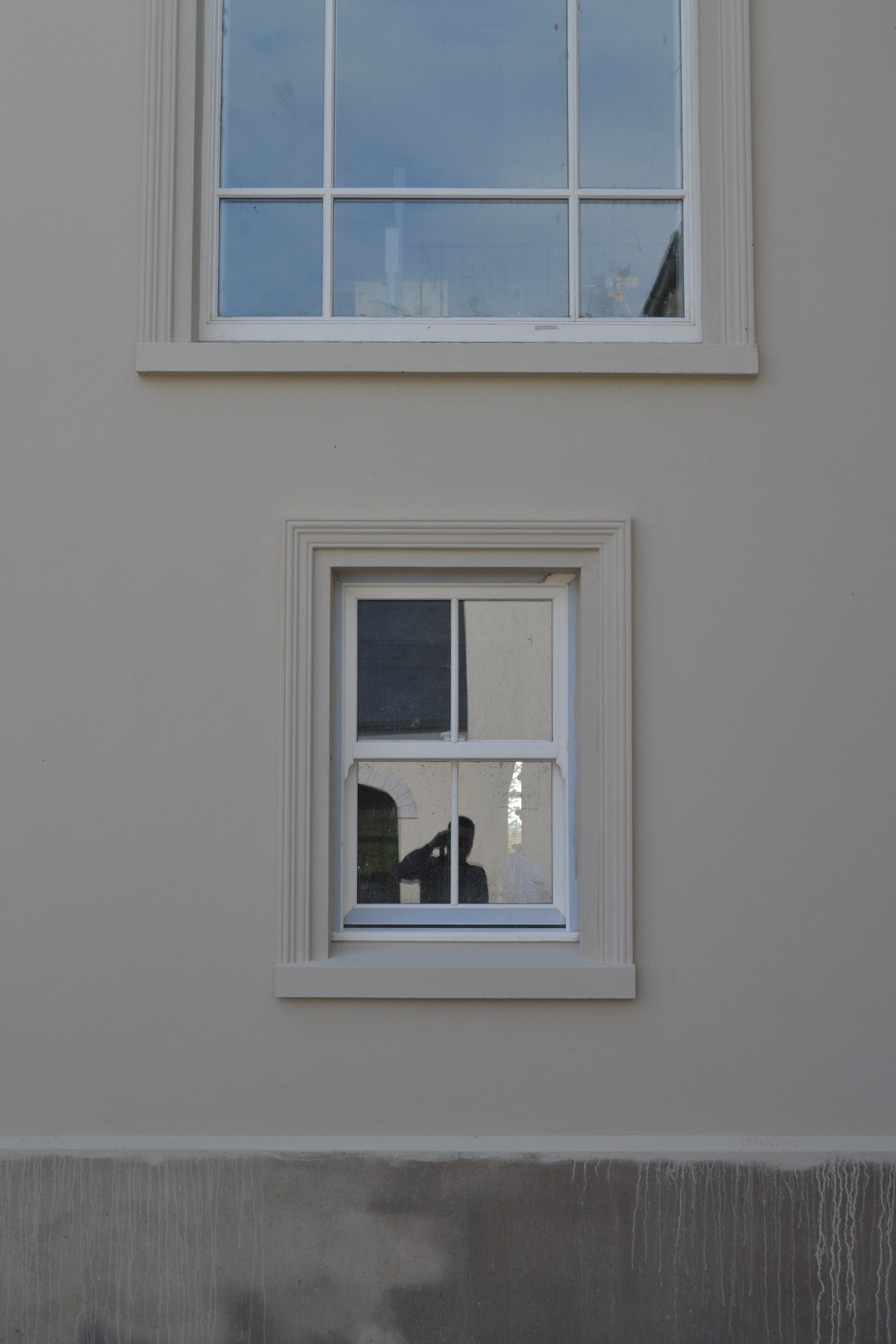 A window on the side of a building with a reflection of a building in the window.