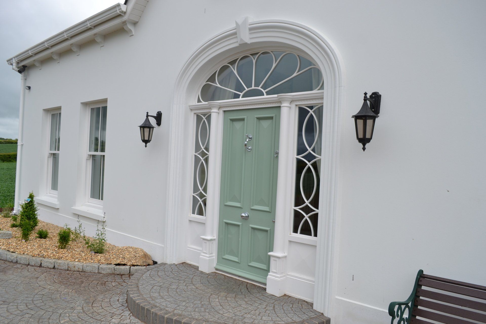 A white house with a green door and a bench in front of it