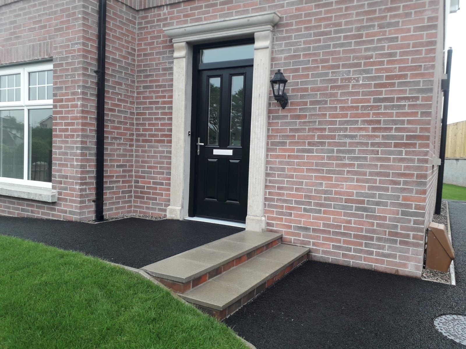 A brick house with a black door and steps