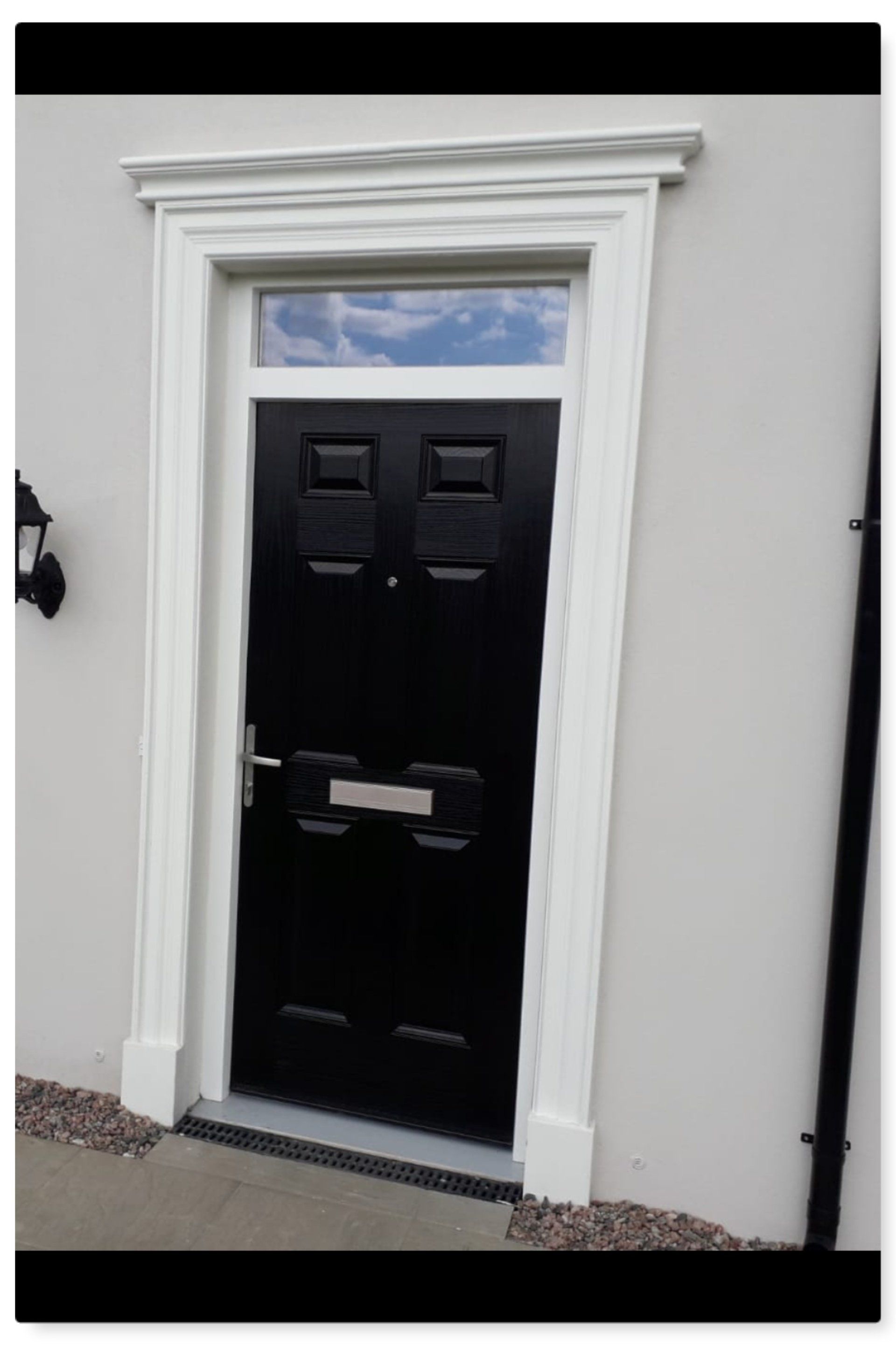 A black door with a white trim is on a white building.