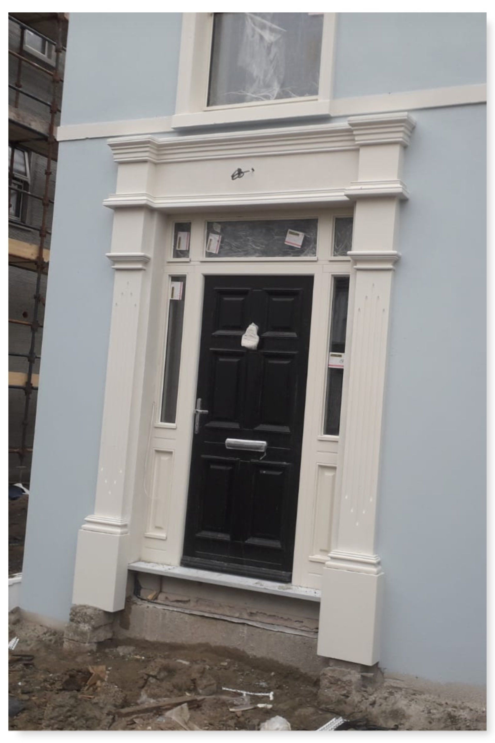 A black door with a white frame is on the side of a building.