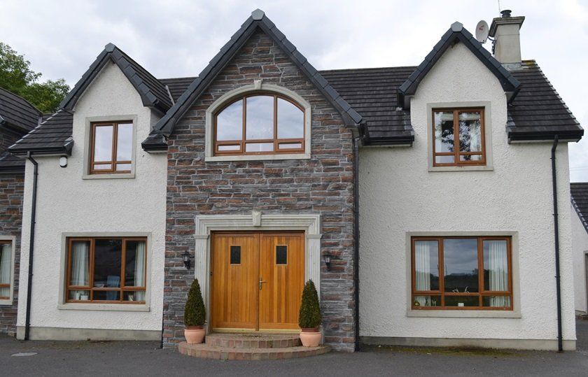 A large white house with a stone facade and a wooden door