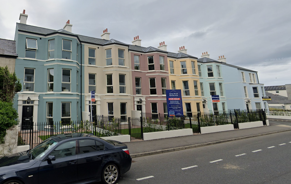 A car is parked in front of a row of houses