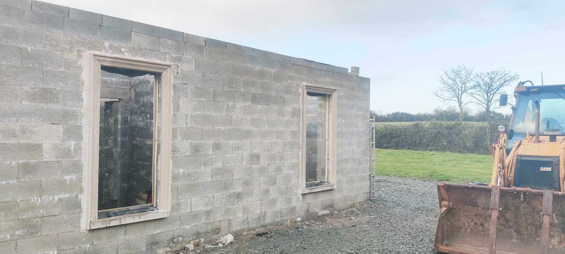 A bulldozer is standing in front of a brick building under construction.