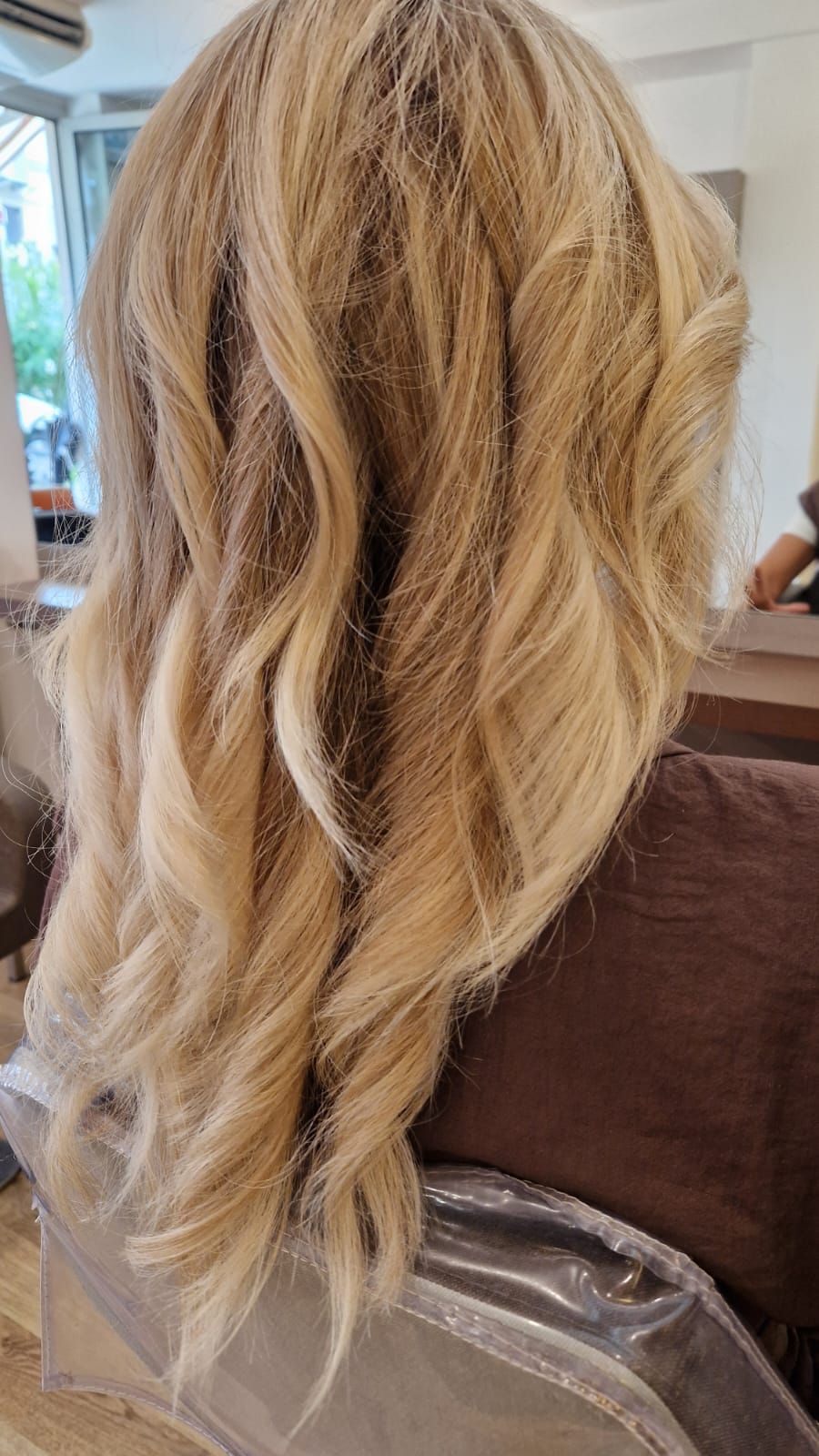 Capelli biondi e ondulati acconciati in un salone di bellezza; vista posteriore.