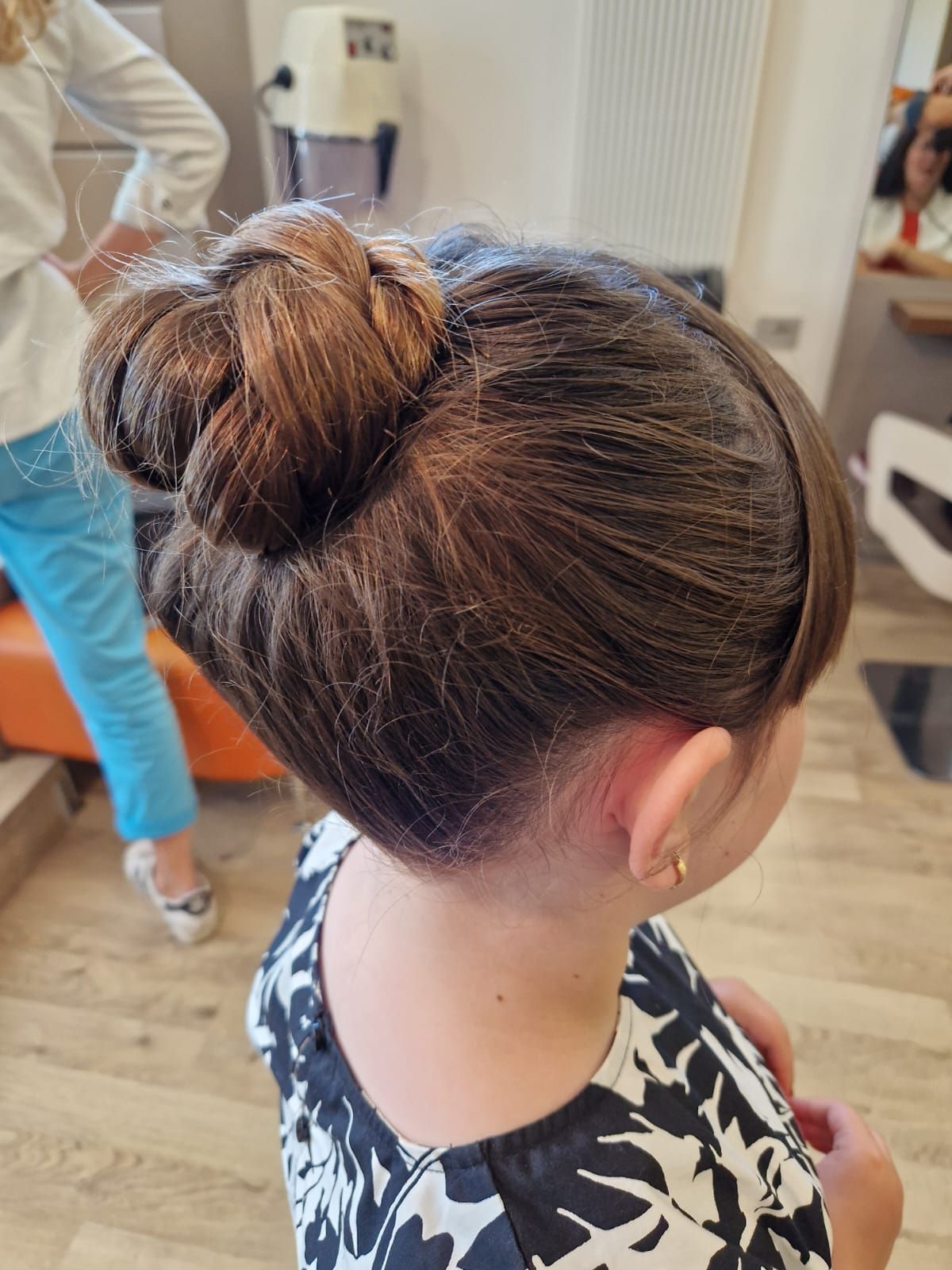 Ragazza con i capelli castani e un'acconciatura raccolta con trecce in un salone di bellezza.