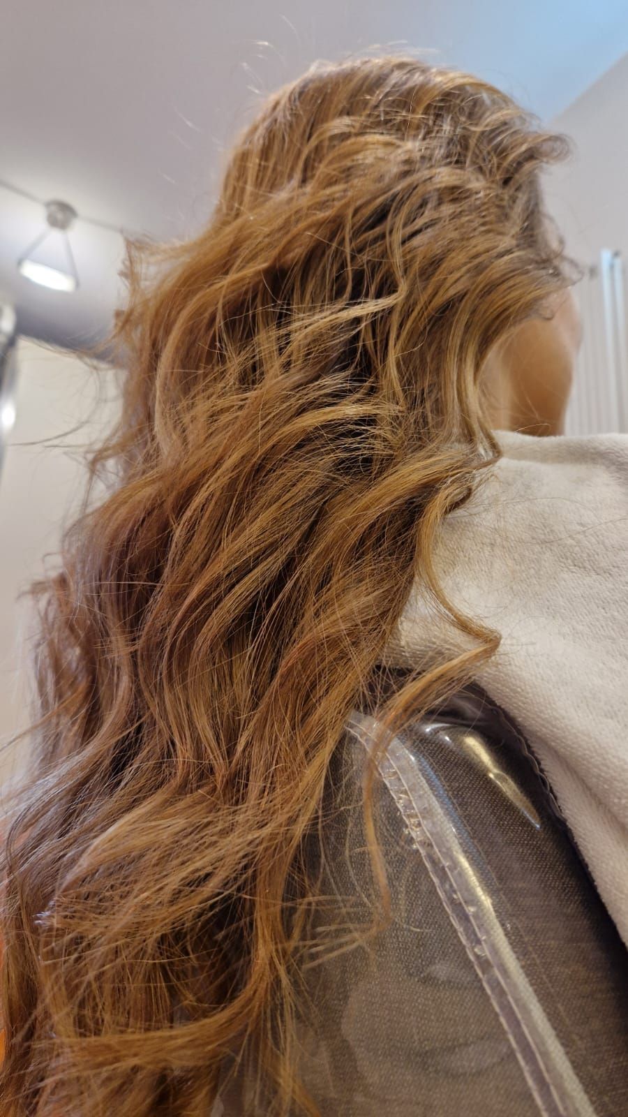 Capelli castani lunghi e ondulati, acconciati in un salone di bellezza.