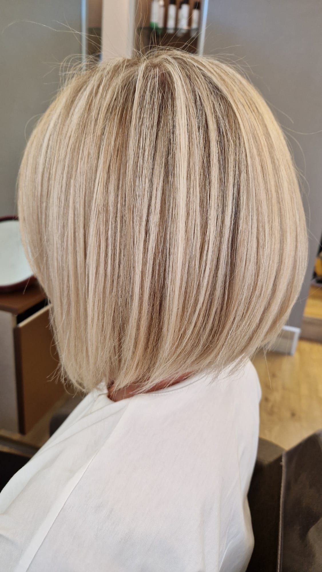 Donna con caschetto biondo arricciato, indossa una camicia bianca.