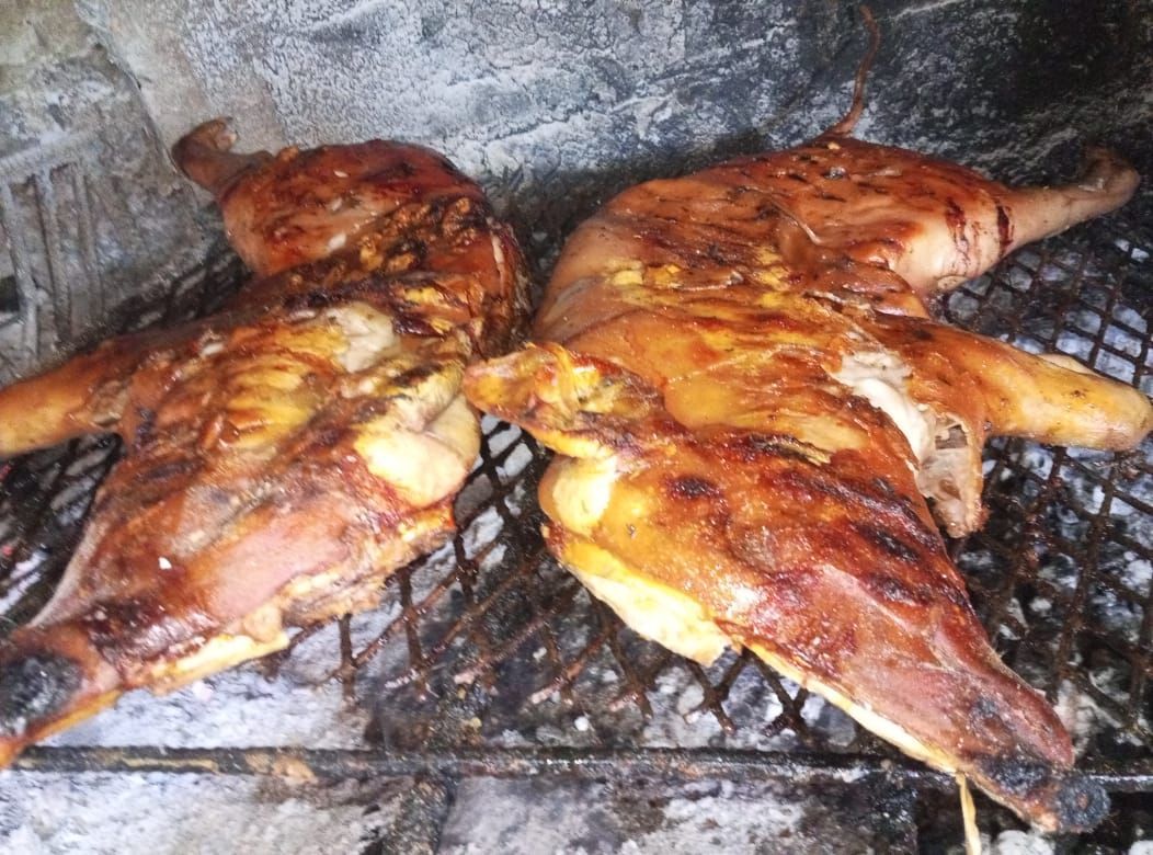 Dos pollos dorados a la parrilla sobre una rejilla de metal.