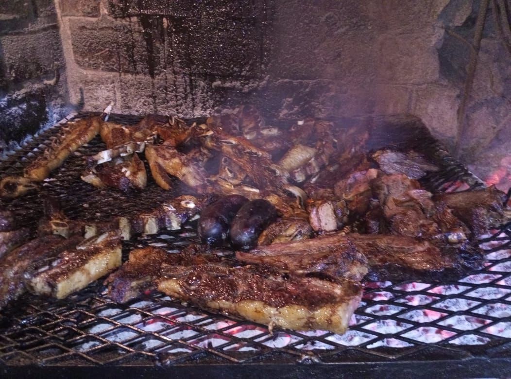 Carne asada sobre brasas en una barbacoa de ladrillo.