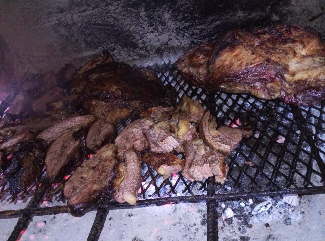 Carne y patatas asándose en una parrilla de carbón.