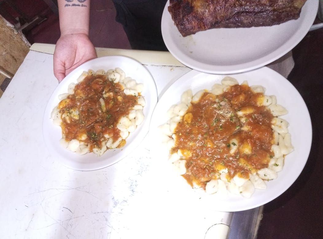 Platos de pasta con salsa, acompañados de un plato de carne.