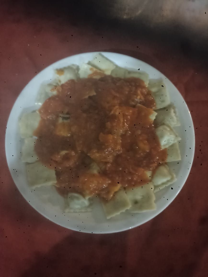 Plato de ravioles en salsa roja.