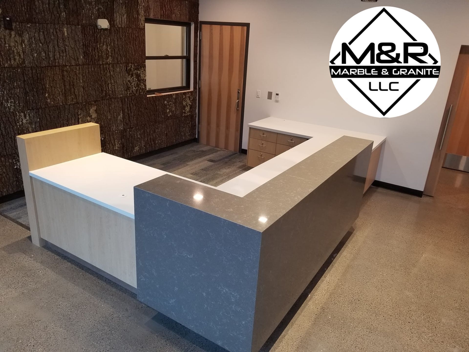 A marble and granite counter in a room with a logo for m & r marble & granite llc