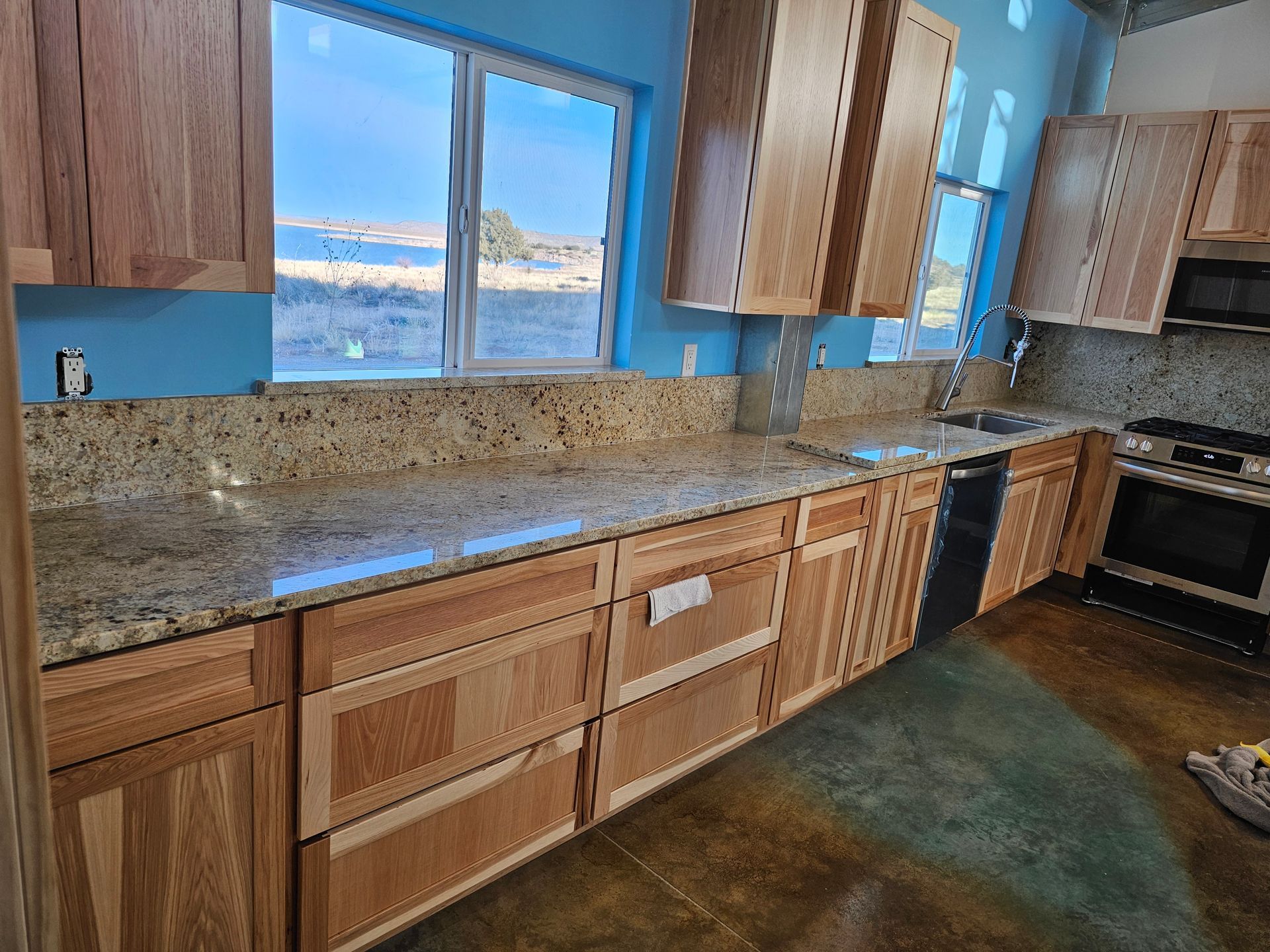 Kitchen with light wood cabinets, granite countertops, and blue walls.