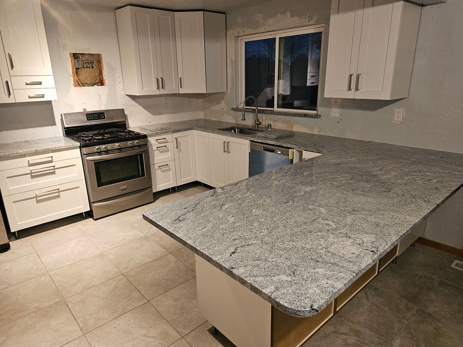 A kitchen with white cabinets, gray countertops, and stainless steel appliances.
