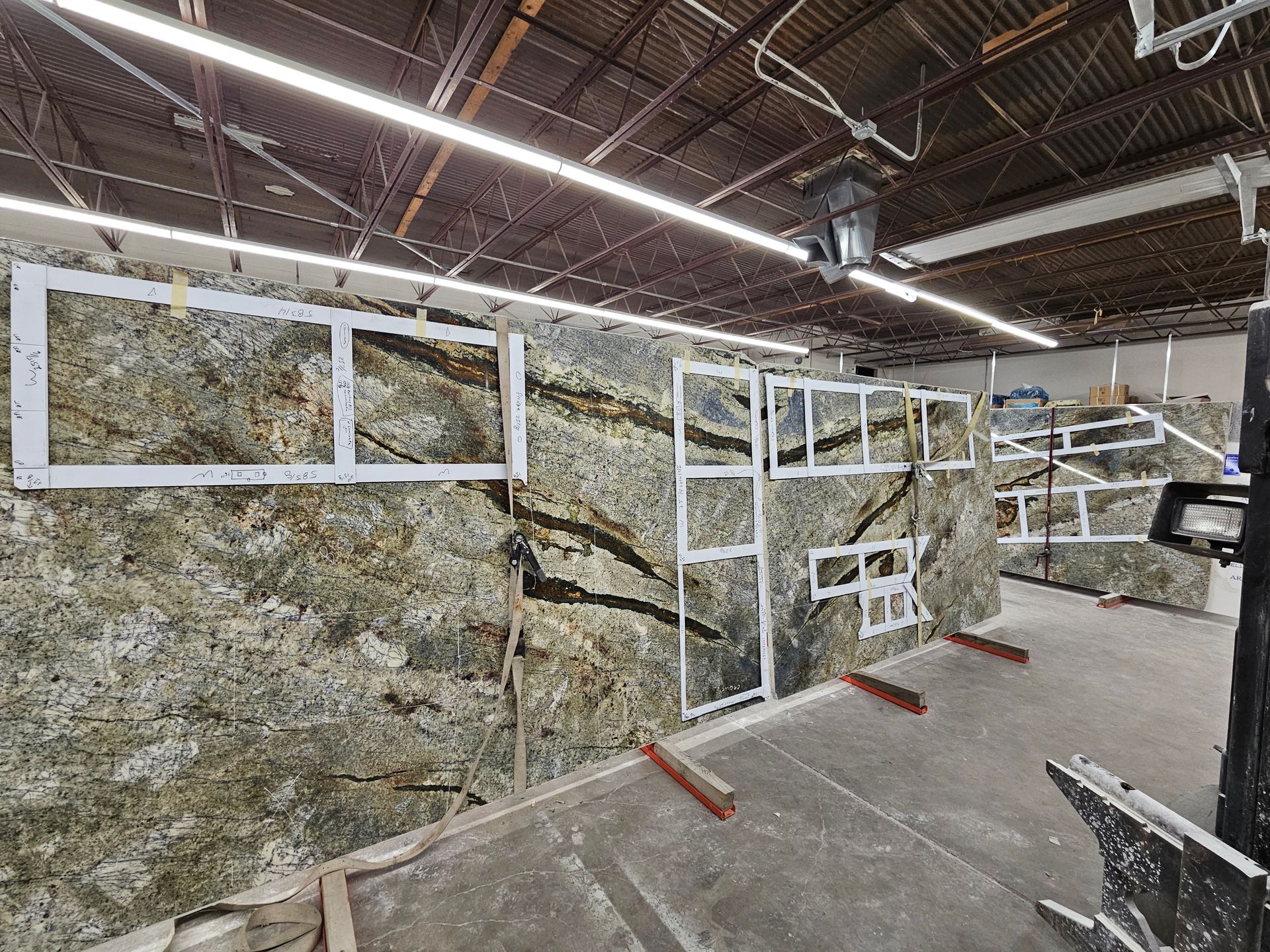 Large granite slabs with metal frames in a workshop, showcasing natural stone patterns and textures.