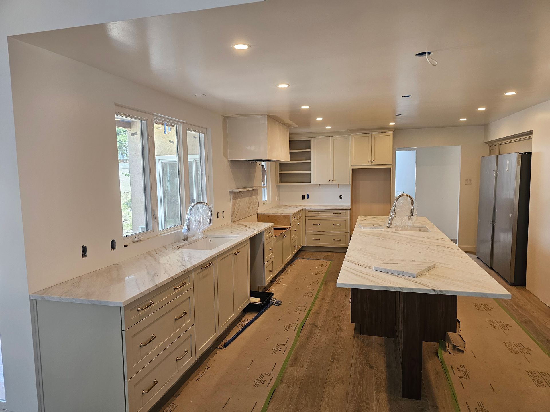 White kitchen with marble countertops, cabinets, and an island.