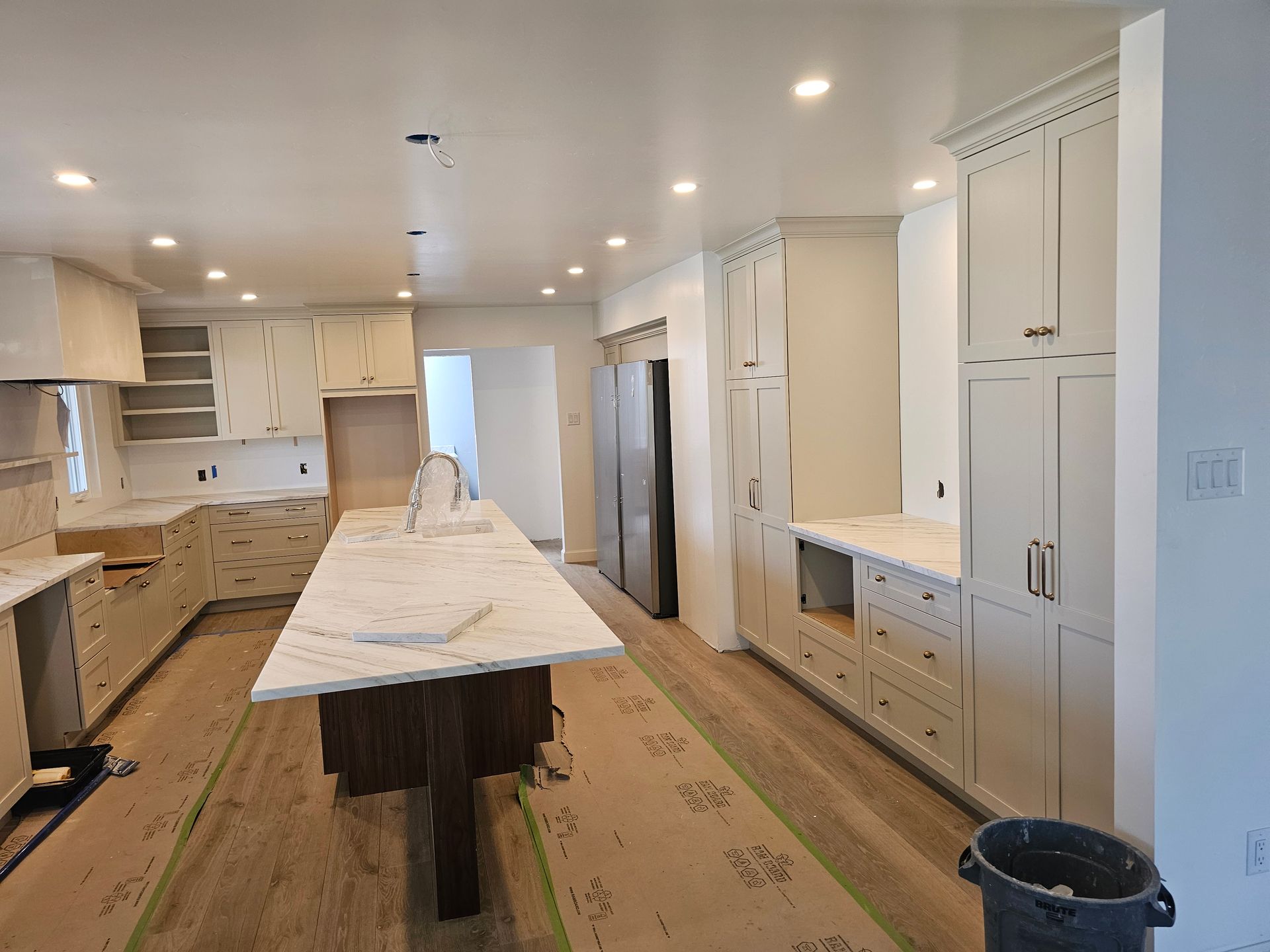Newly renovated kitchen with light cabinets, marble countertops, and a large island.