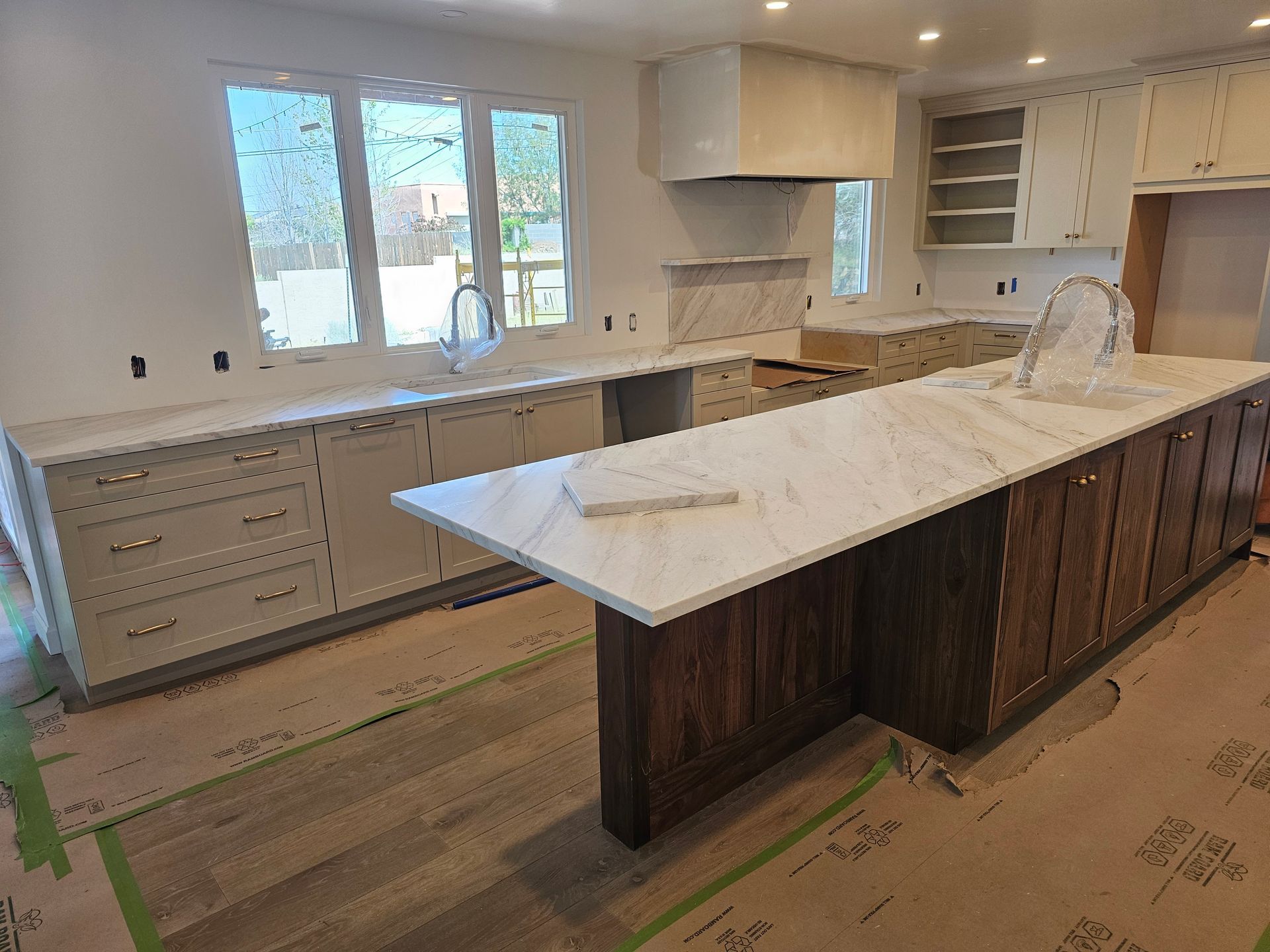 A kitchen with white countertops and cabinets, a wood island, and a window.