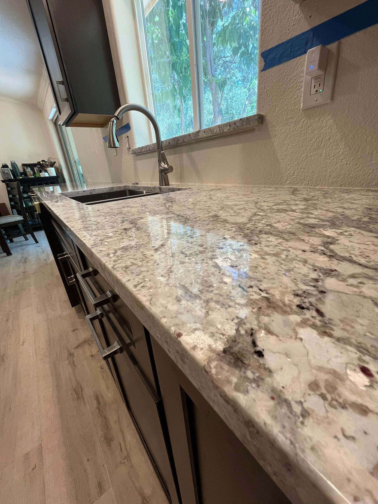 Granite countertop with a silver faucet and a window in the background. Kitchen remodel in progress.