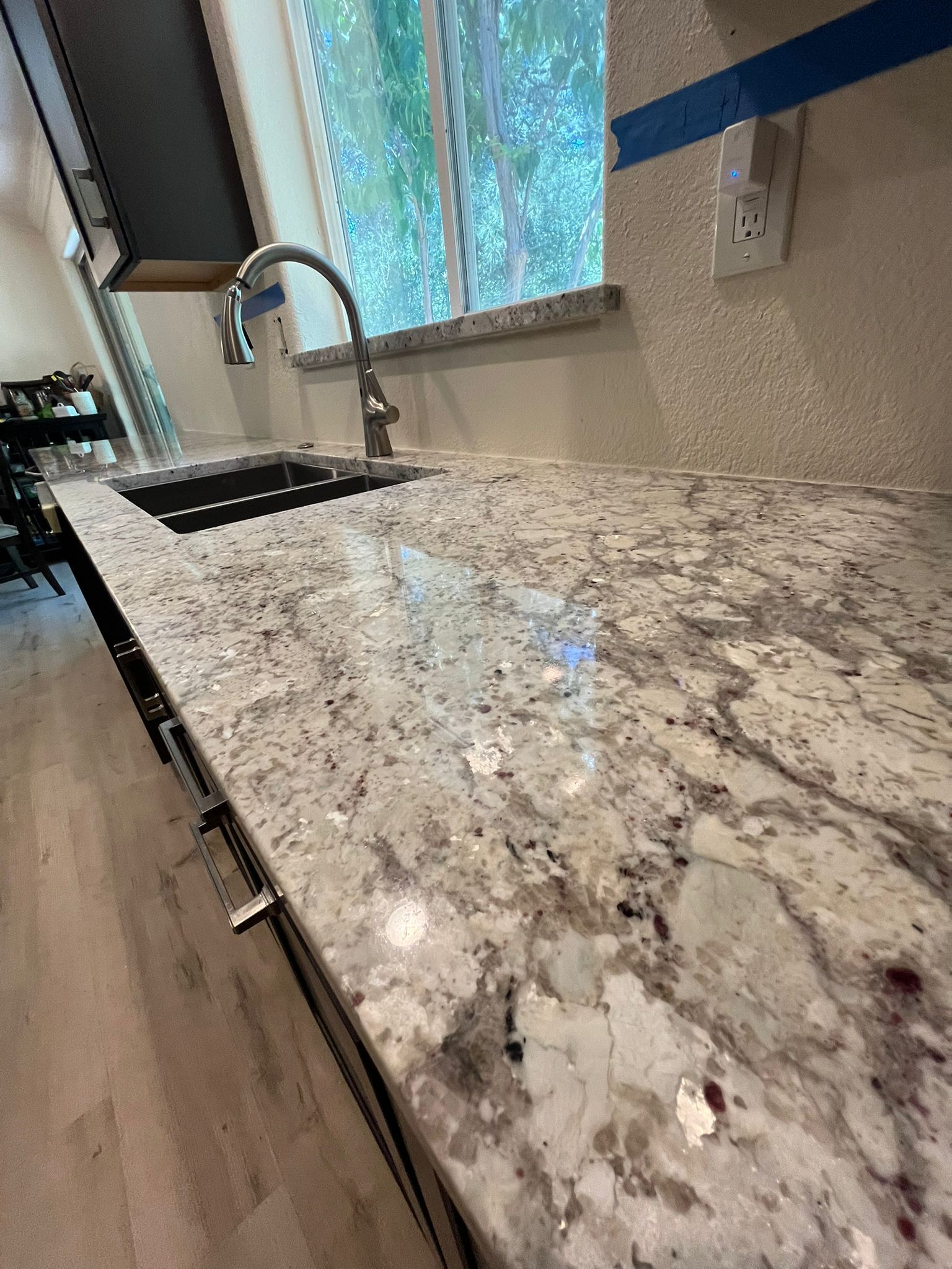 Granite countertop with a sink and faucet, next to a window.