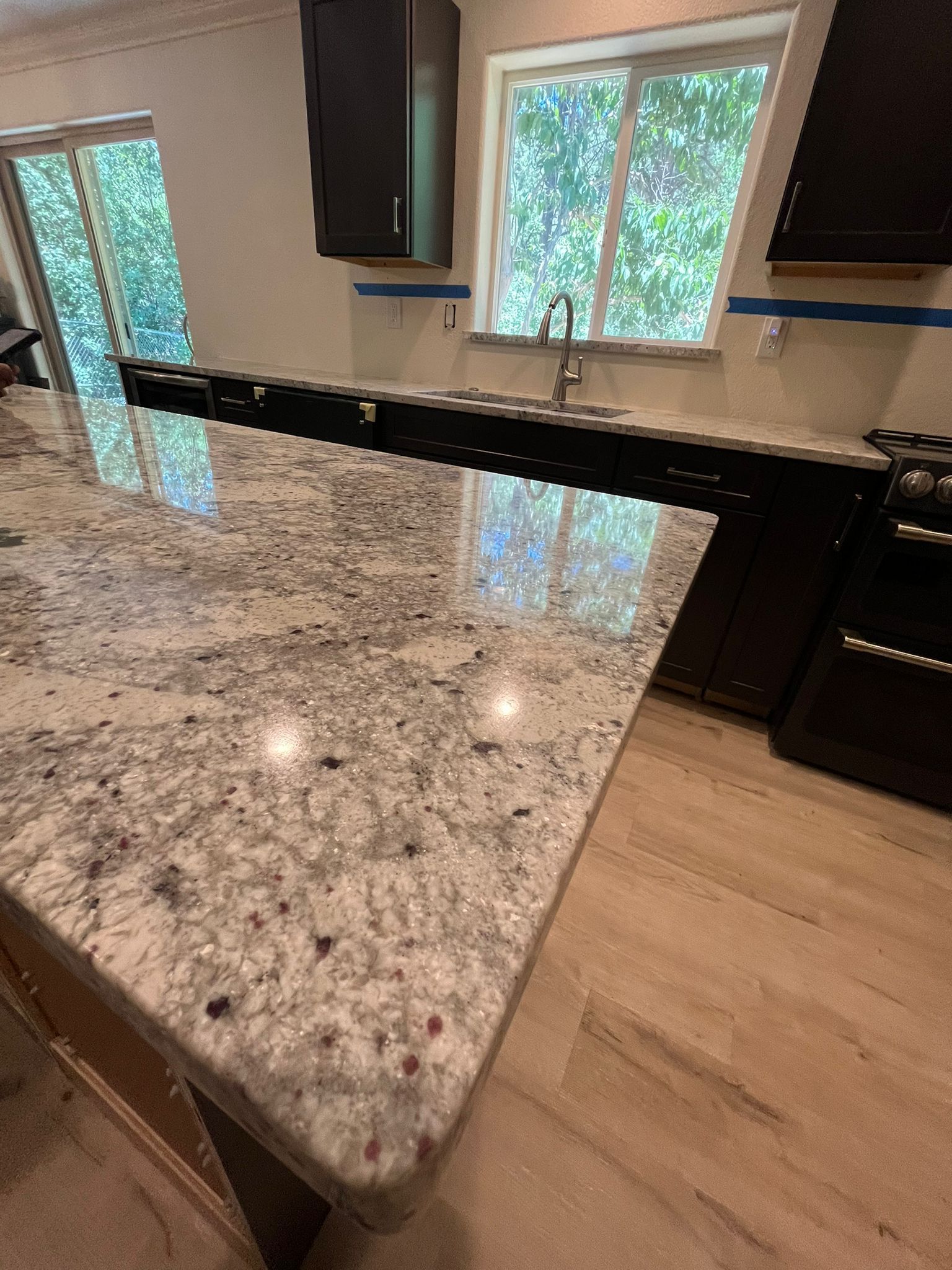 Granite countertop in a kitchen, near a window. White and gray pattern, with a rounded edge.