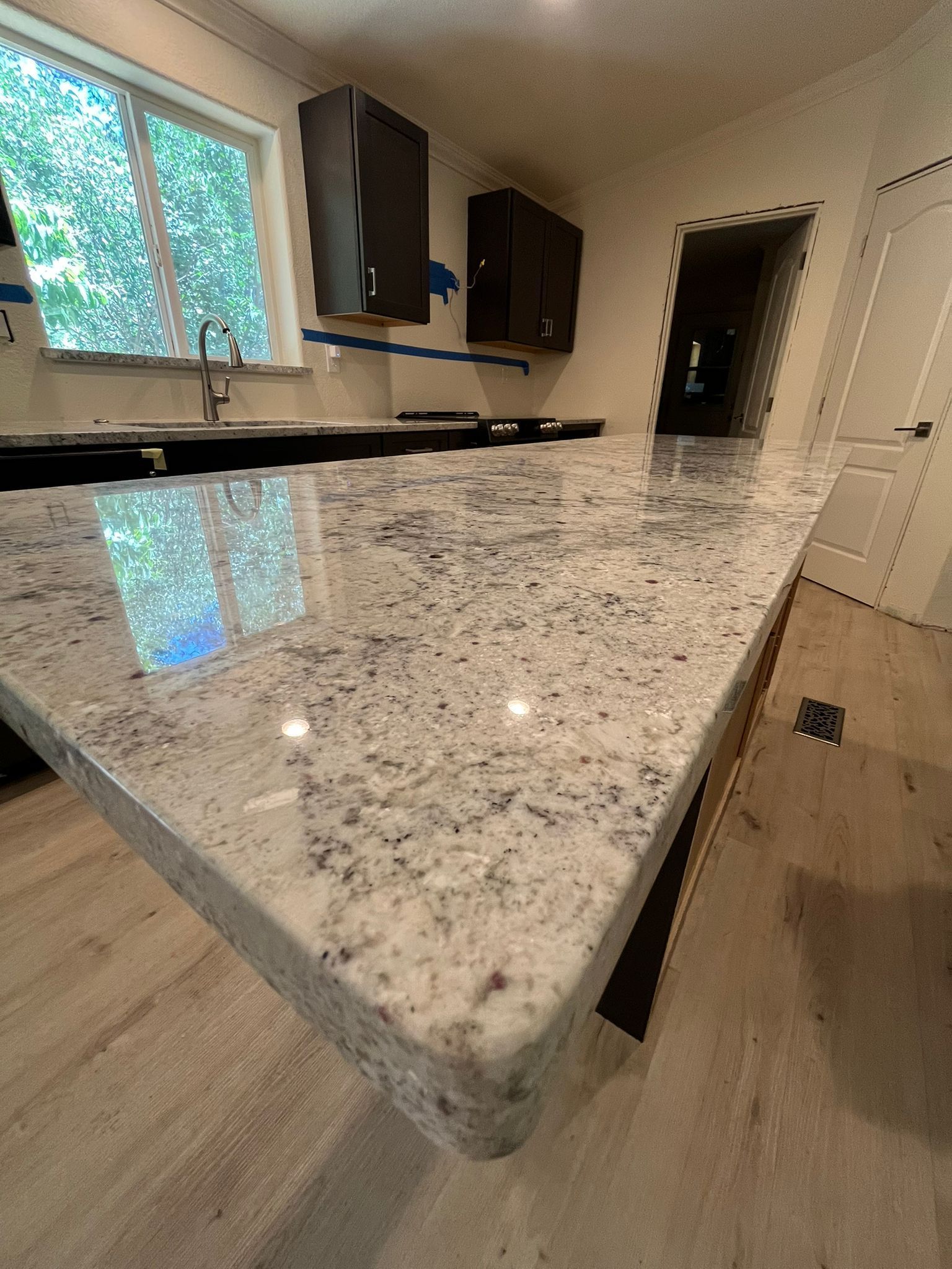 Kitchen with white and gray granite countertop and dark cabinets.