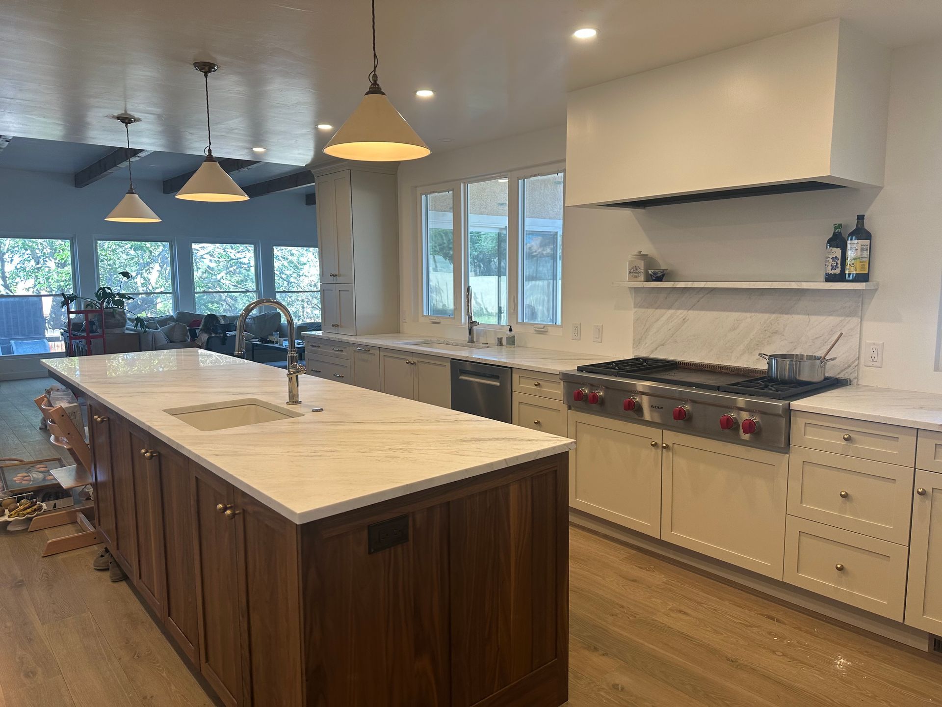 Modern kitchen with white cabinets, marble countertops, and a dark wood island.