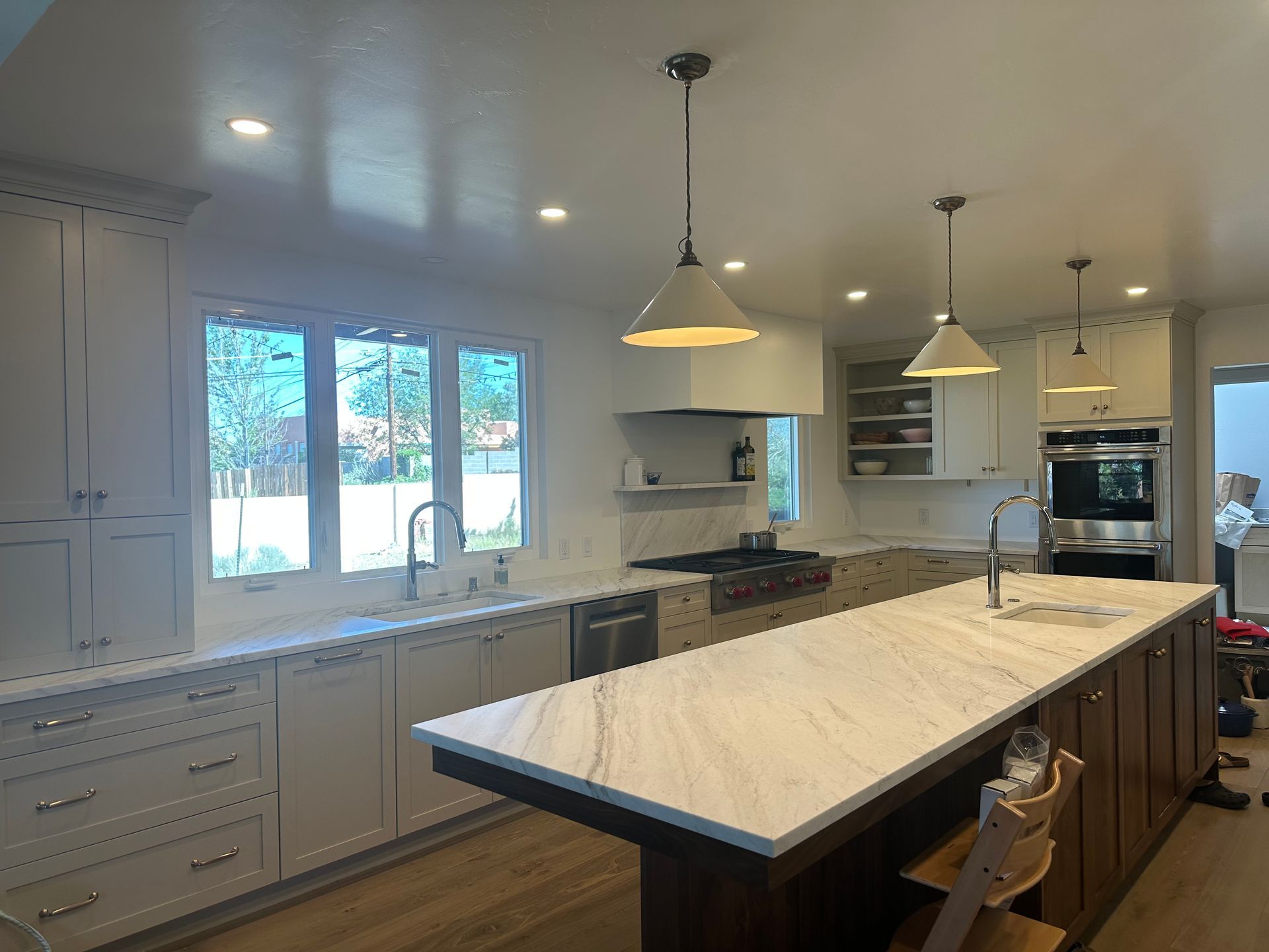 Kitchen with white cabinets, large island, stainless steel appliances, and pendant lights.