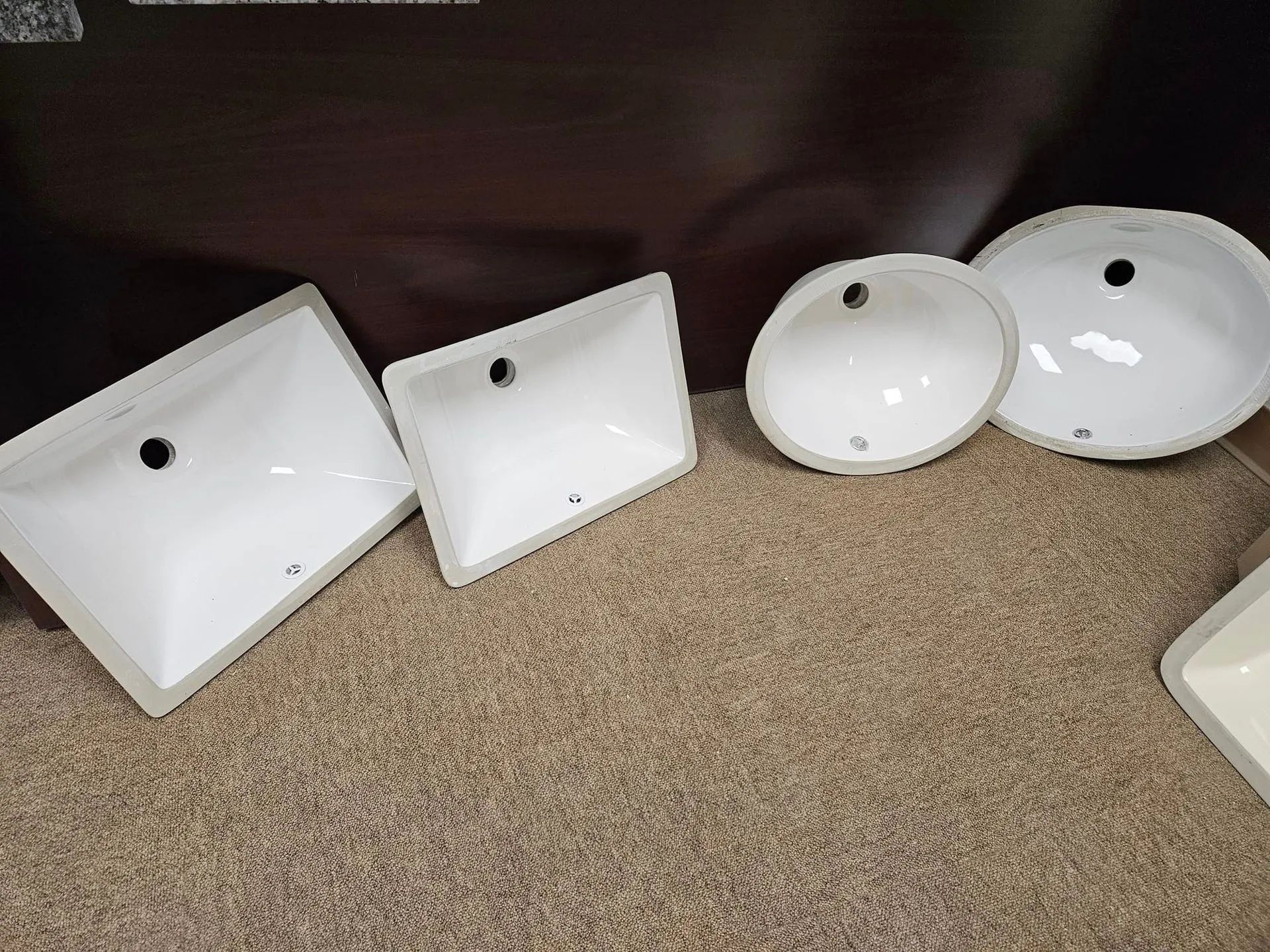 A group of white sinks are sitting on a carpeted floor.